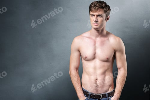 Preview: Male person stands with bare torso against simple background in indoor space