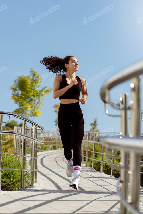 Preview: Full length shot of healthy young woman running on the summer promenade