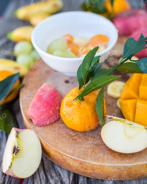 Preview: Apples, tangerines, bananas, mangoes and grapes on a wooden board