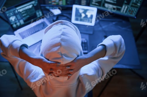Preview: Young professional female hacker is indoors by computer with lot of information on displays