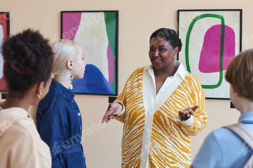 Preview: Black woman giving tour to group of teenagers in art gallery