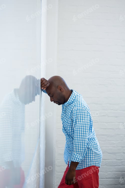 Preview: Upset man with eyes closed and hand on the forehead leaning against a wall