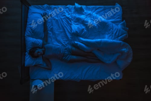 Preview: The woman sleeping on the bed. Evening night time. View from above.