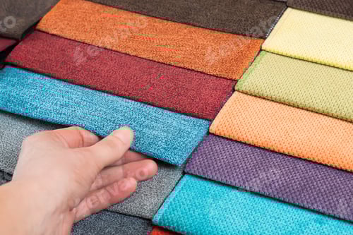 Preview: Woman hand chooses samples of colored fabric on table close up