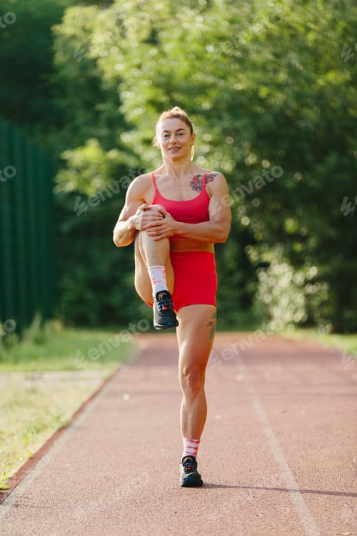 Preview: Strong woman stretching leg on outdoor running track