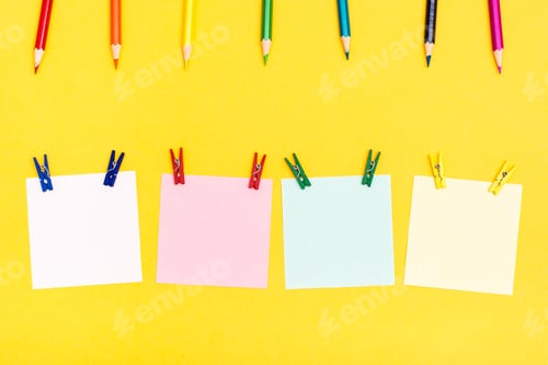 Preview: Colored wooden pencils, pins and sheets for writing on a yellow background. Rainbow palette
