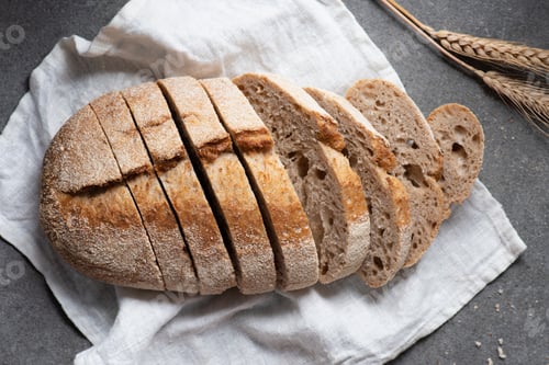 Preview: flat lay with cut loaf of bread on white linen on grey tabletop