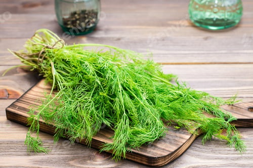Vista previa: A bunch of fresh dill on a cutting board on a wooden table