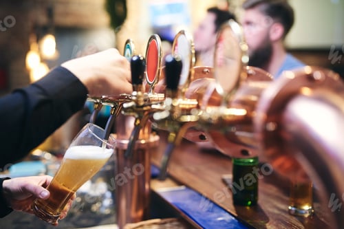 Preview: Bartender's hand pouring customer a mug of cold beer