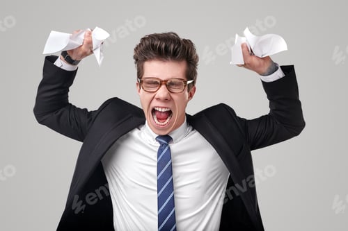 Preview: Angry businessman crumpling documents in studio
