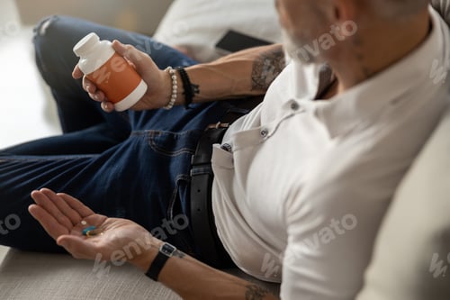 Preview: Male is examining a bottle of pills