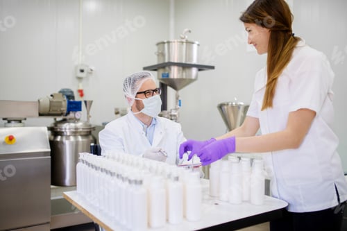 Preview: Two Young Healthcare Factory Employees Charging Bottles With Face Cream.