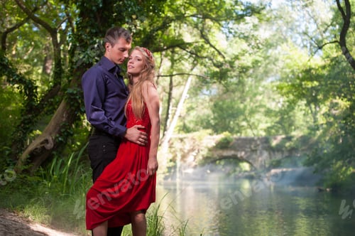 Preview: young handsome guy with a girl hugging in the summer on the river bank in the forest