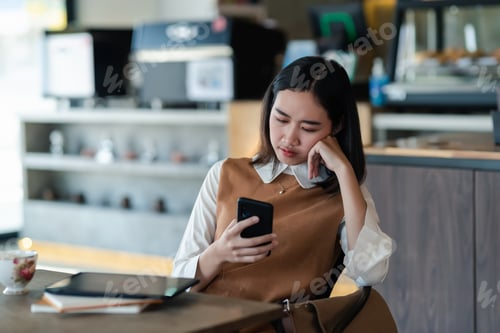 Preview: Young Asian businesswoman think and using a smartphone at the office.