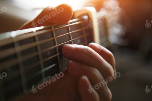 Preview: A man's hand on the fretboard of a guitar runs his fingers through the strings