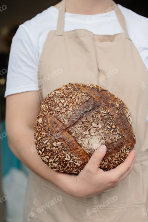 Preview: Close up of female baker holding freshly baked bread.