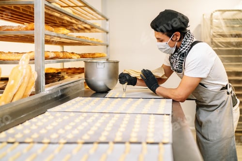 Preview: close-up of a pastry chef with confectionary bag squeezing cream in the pastry shop or bakery