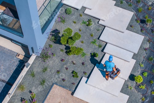 Preview: Landscaper Working on Modern Garden Pathway in Sunlit Outdoor Space