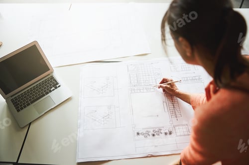 Preview: Beautiful elegant lady in pink clothes is working with blueprints in the working space