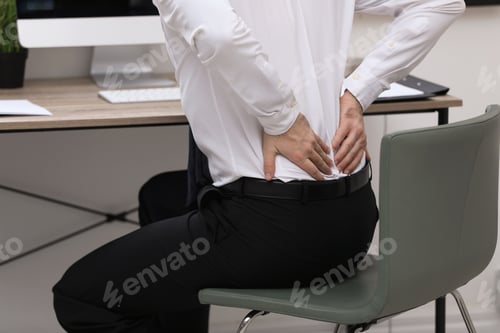 Preview: Businessman suffering from back pain at workplace, closeup