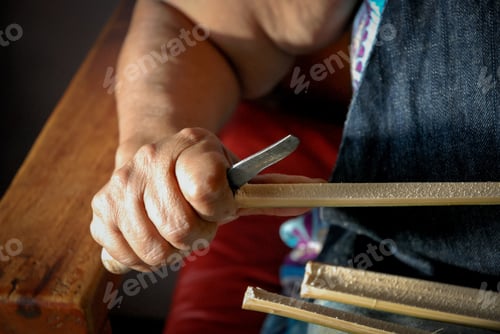 Preview: Closeup shot of a female craftsperson sharpening a piece of wood with a knife