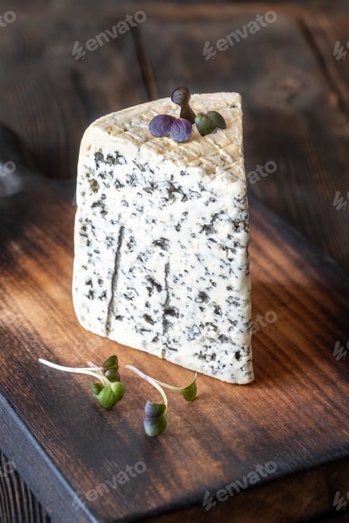 Preview: Wedge of Roquefort cheese resting on a rustic wooden cutting board