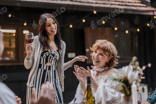 Preview: Friends celebrating with wine at outdoor party