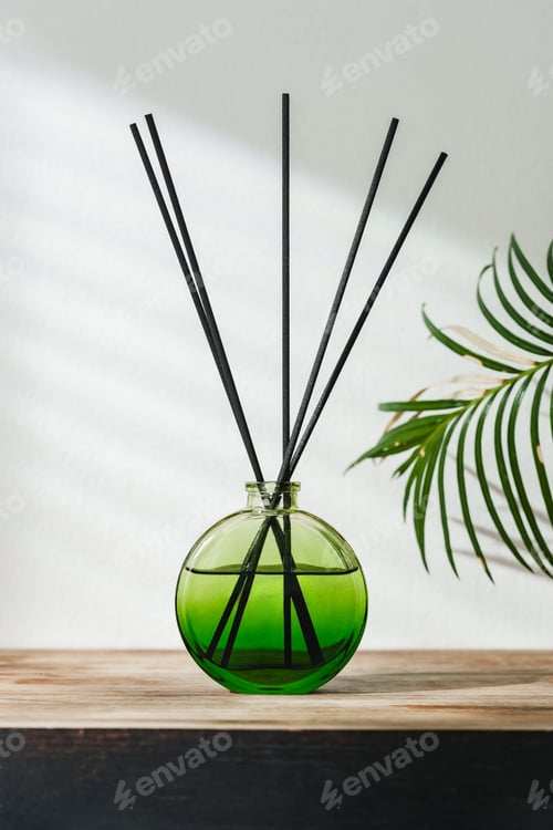 Preview: Aromatic Reed Diffuser on Wooden Table With Vibrant Green Leaves Against White Background