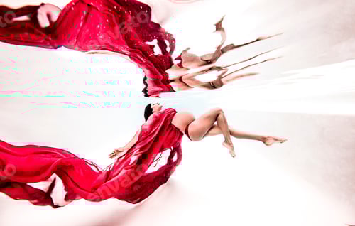 Preview: Underwater view of poised young pregnant woman with flowing red textile