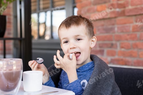 Visualização: um garotinho de aparência europeia come em um café de rua