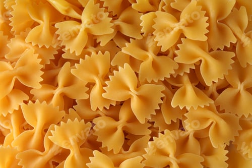 Preview: Many yellow close up of bowtie pasta. Texture. Pattern.