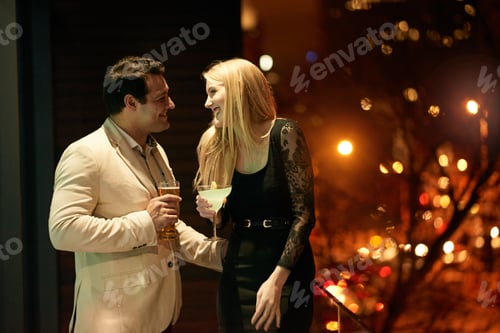 Preview: Cropped shot of a young couple enjoying drinks on a balcony during a party