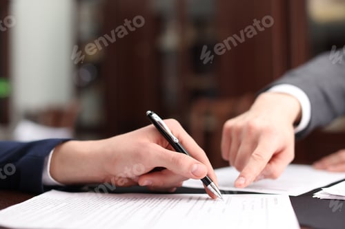 Preview: Notary showing client where to sign document in office, closeup