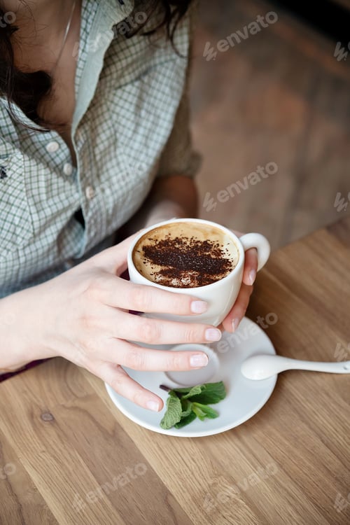 Preview: ↟ Young girl drinking coffee in a cafe. Hands of a woman with a cup of hot drink close-up
