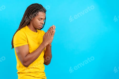 Preview: Latin man with dreadlocks praying with eyes closed