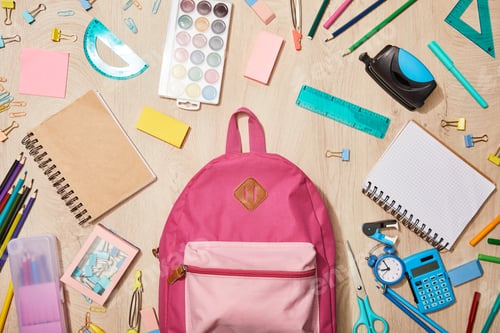 Preview: top view of various school supplies with pink backpack on wooden desk
