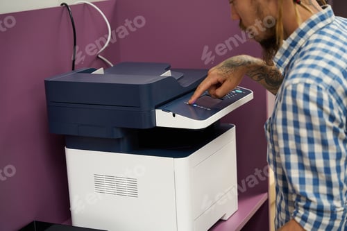Preview: Freelancer with dreadlocks uses a photocopier in a coworking space