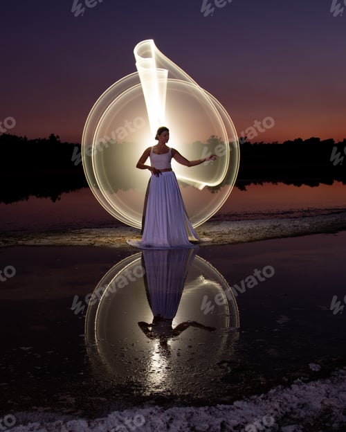 Preview: Woman posing for light painting with bright lights in the dark. Reflection in the water