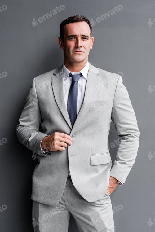Preview: Smart and Successful. Businessman in suit posing isolated over grey background