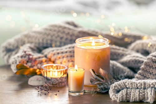 Preview: Cozy composition with candles and a knitted element on a blurred background.