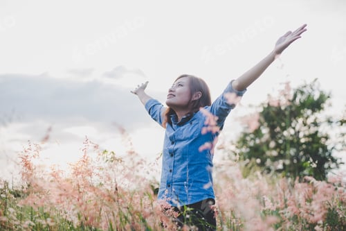 Preview: Beautiful woman standing stretch her arms in the air on the grass field. Woman enjoy with nature.