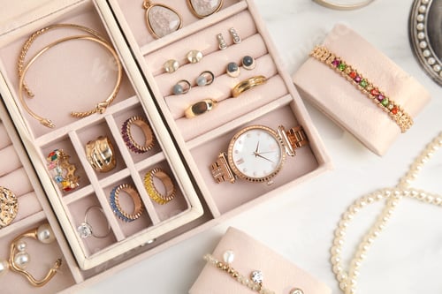 Preview: Jewelry box with stylish golden bijouterie on white table, flat lay