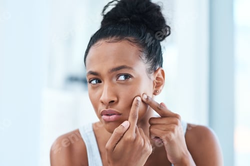 Preview: Not you again. Cropped shot of a beautiful young woman squeezing a pimple in the mirror.