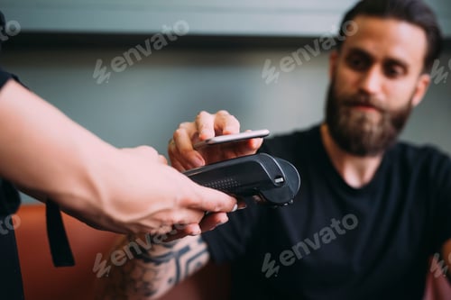 Preview: Client making a contactless payment at a barber shop with a focused barber watching.