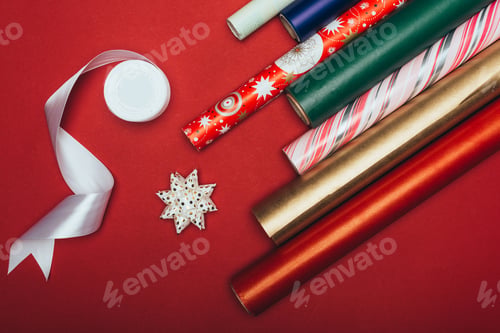 Preview: top view of wrapping paper rolls, ribbon and bows on red