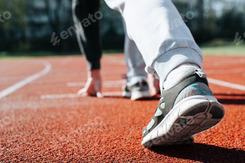 Preview: Close-up of woman practicing running in stadium, standing at low start on sunny day. Sportswoman