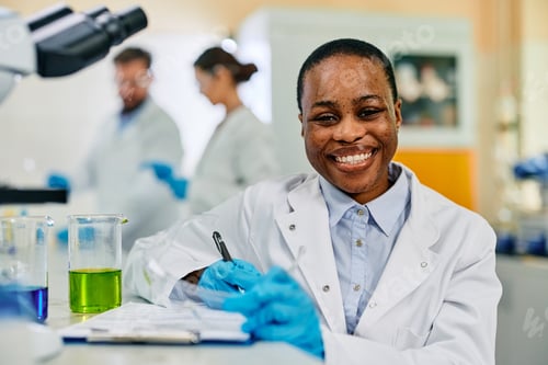 Preview: Happy African American female scientist in lab looking at camera.