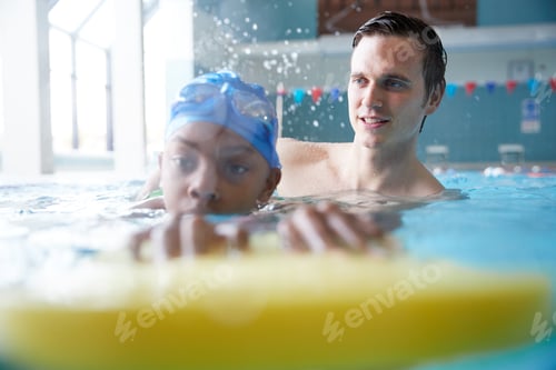 Preview: Male Swimming Coach Giving Boy Holding Float One To One Lesson In Pool