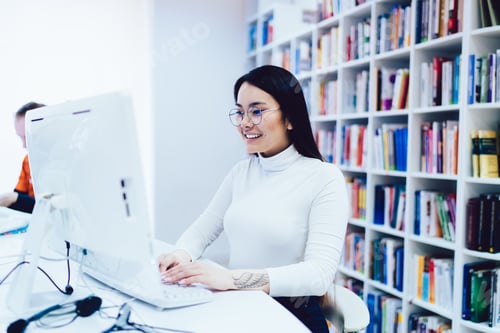 Preview: Cheerful woman smiling and using computer