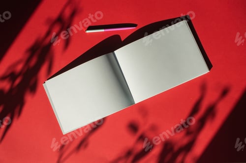 Preview: A notepad with a pen lies on a colored red background. Office supplies. Place for text